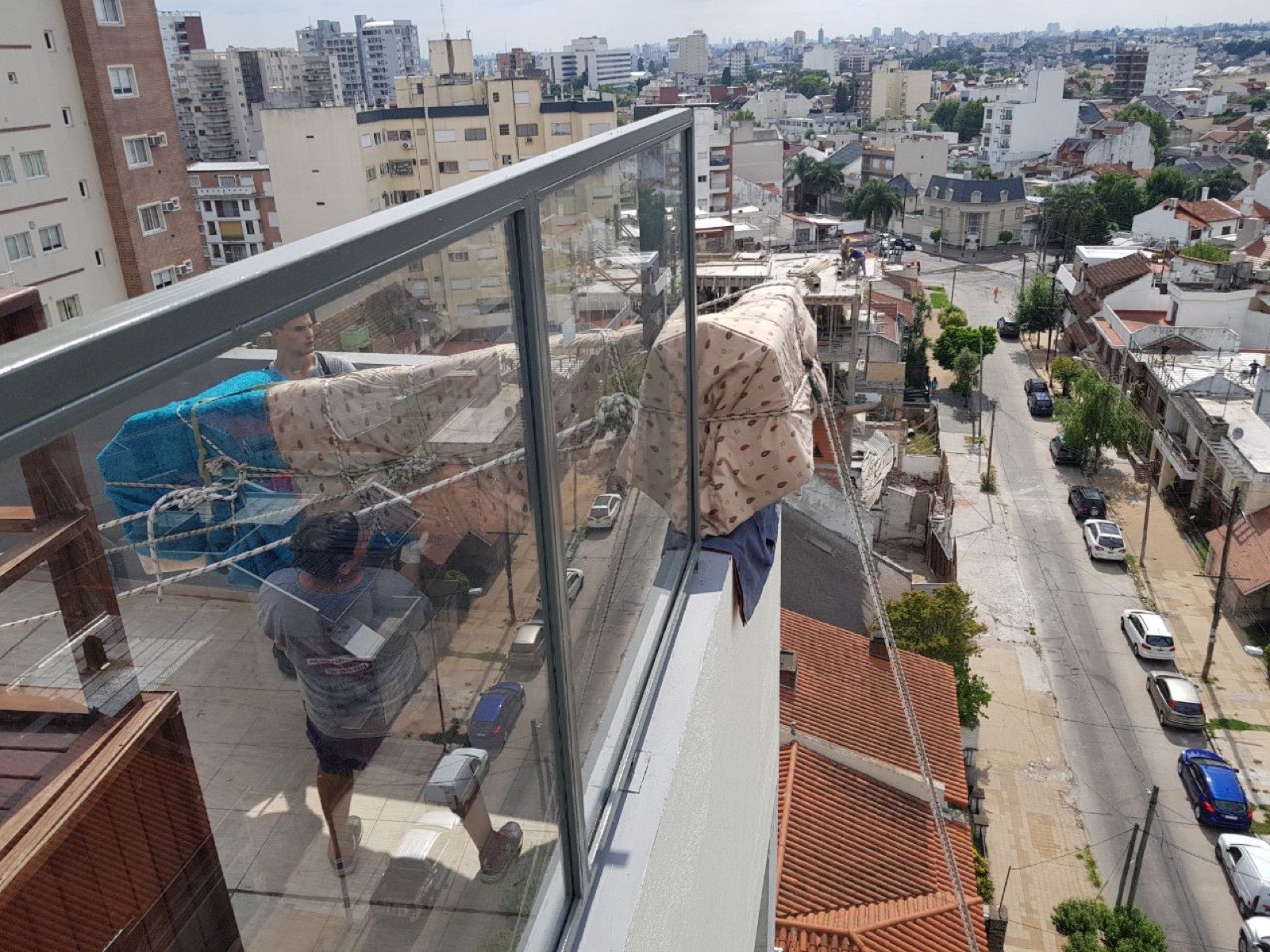 Muebles embalados bajando con sogas desde el balcón de un piso alto